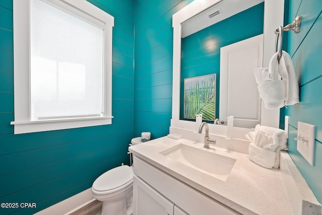 half bath with visible vents, toilet, and vanity