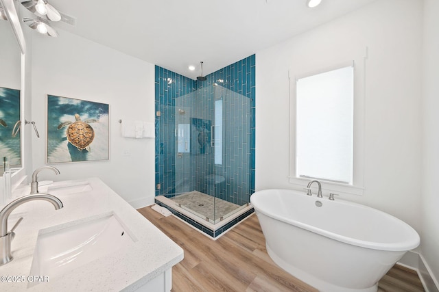 bathroom featuring a shower stall, a soaking tub, wood finished floors, and a sink