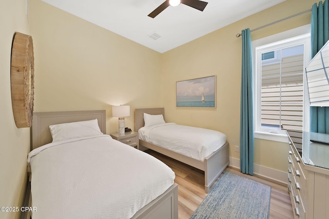 bedroom with light wood-style floors, visible vents, baseboards, and ceiling fan