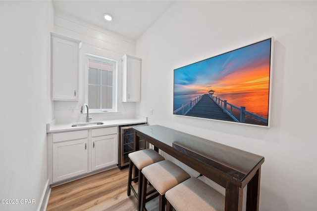 bar featuring light wood-type flooring, wine cooler, a sink, and recessed lighting