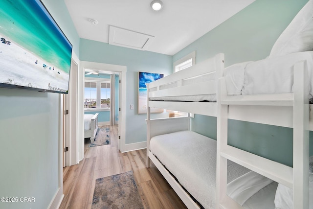 bedroom with attic access, baseboards, and wood finished floors