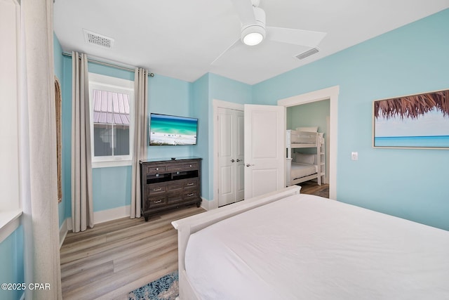 bedroom with wood finished floors, visible vents, baseboards, and ceiling fan