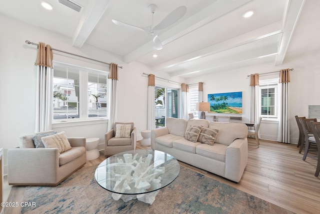 living room with baseboards, wood finished floors, beam ceiling, and visible vents
