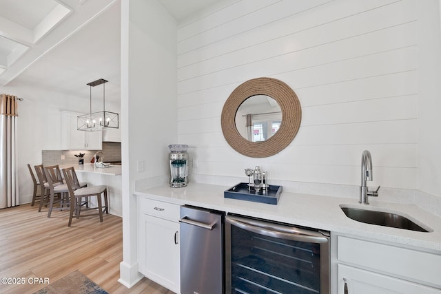 bar with a sink, light wood-type flooring, decorative backsplash, indoor wet bar, and beverage cooler