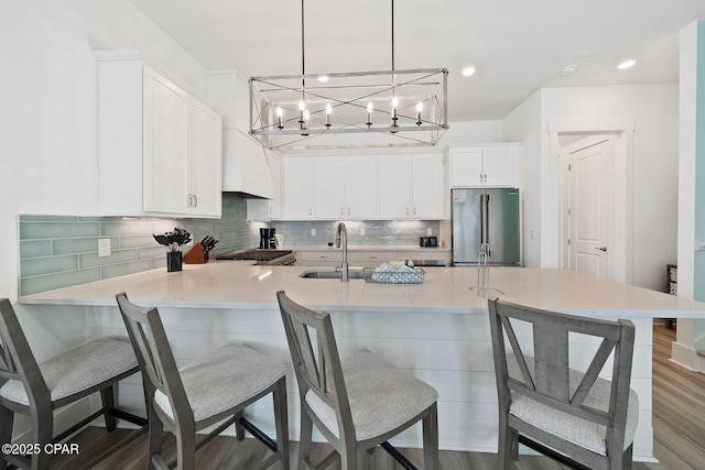 kitchen featuring high quality fridge, white cabinetry, a breakfast bar area, and tasteful backsplash