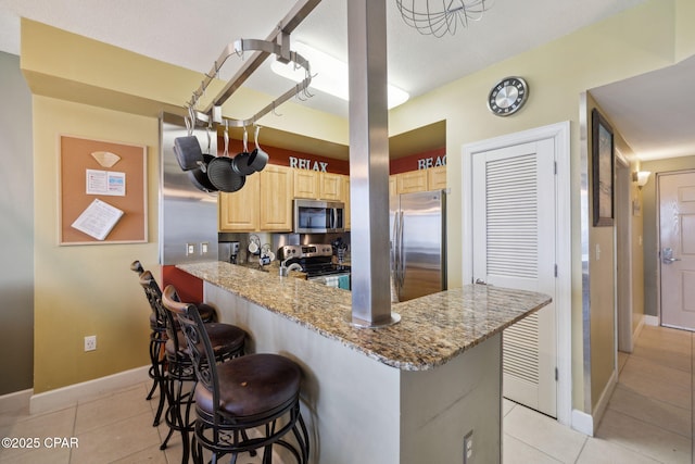 14825 Front Beach Rd Unit 2205, Panama City Beach, FL 32413 - kitchen featuring a breakfast bar area, light brown cabinetry, baseboards, appliances with stainless steel finishes, and light tile patterned flooring