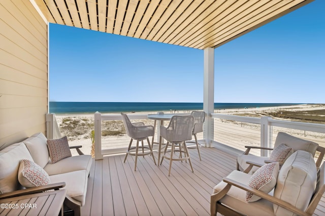 wooden deck featuring a beach view and a water view