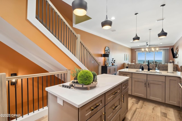 kitchen with light wood finished floors, a center island, a sink, a ceiling fan, and light countertops