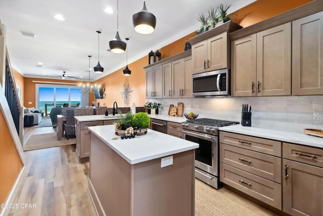 kitchen featuring a ceiling fan, a sink, decorative backsplash, stainless steel appliances, and a kitchen island