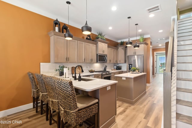 kitchen featuring tasteful backsplash, a sink, a peninsula, appliances with stainless steel finishes, and visible vents