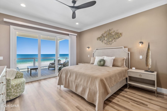 bedroom featuring recessed lighting, access to exterior, a water view, and light wood-type flooring
