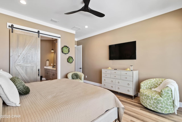 bedroom with a barn door, recessed lighting, visible vents, and light wood-type flooring