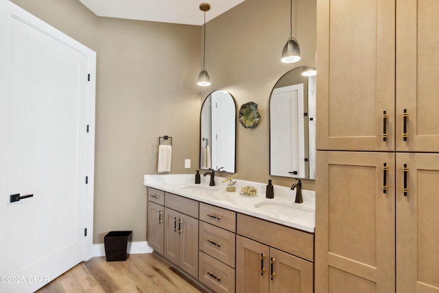 full bathroom with baseboards, wood finished floors, a sink, and double vanity