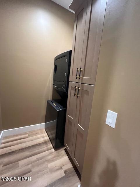 room details with baseboards, stacked washer / dryer, and wood finished floors
