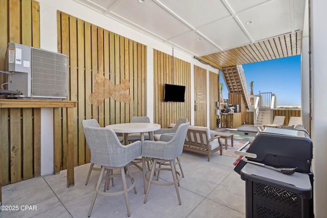 view of patio featuring outdoor dining space, central AC, and stairway
