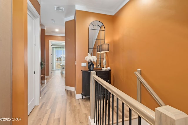 hall featuring baseboards, light wood-style flooring, visible vents, and an upstairs landing