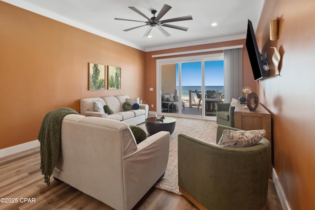 living area with recessed lighting, wood finished floors, ornamental molding, baseboards, and ceiling fan