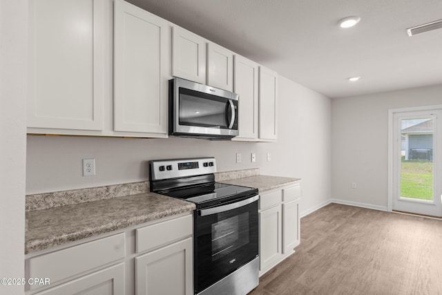 kitchen featuring light wood-type flooring, white cabinetry, and appliances with stainless steel finishes