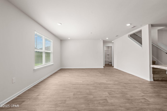 unfurnished living room featuring baseboards, light wood-type flooring, stairs, and visible vents