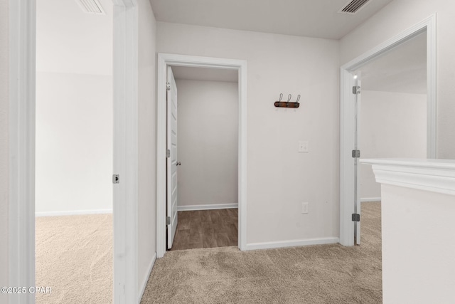 hall featuring carpet floors, baseboards, and visible vents