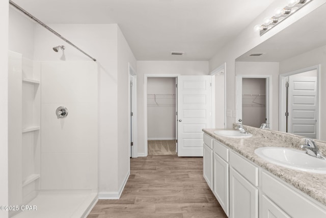 bathroom featuring a sink, a stall shower, wood finished floors, and visible vents