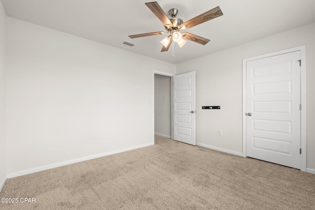 carpeted spare room with visible vents, a ceiling fan, and baseboards