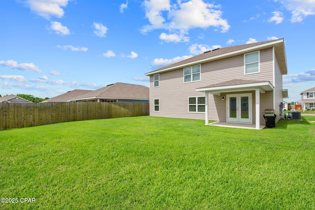 rear view of house with a lawn, a fenced backyard, central AC, and french doors