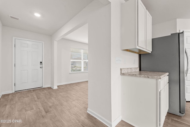 entryway with baseboards, visible vents, and light wood-type flooring