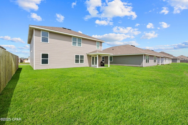 rear view of house featuring a lawn, a patio area, and fence