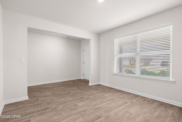 empty room with baseboards and light wood-type flooring