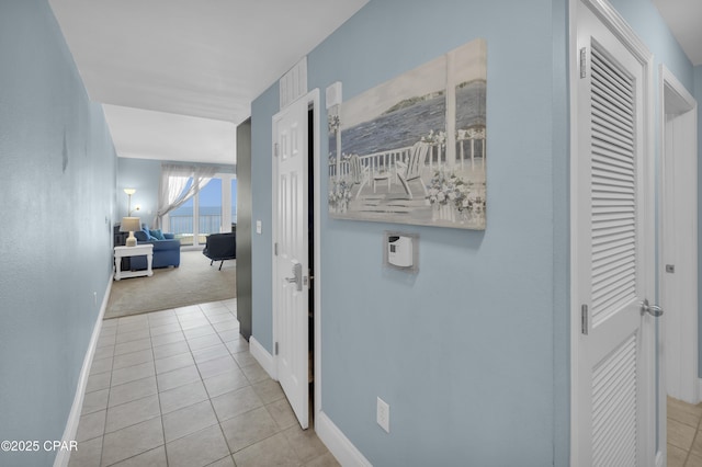 hallway featuring carpet flooring, tile patterned floors, and baseboards