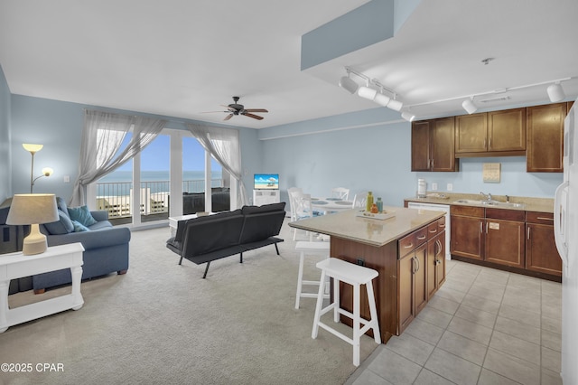 kitchen with a sink, open floor plan, a kitchen bar, ceiling fan, and a kitchen island
