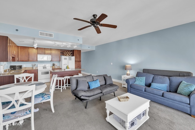 living room with light colored carpet, a ceiling fan, and visible vents
