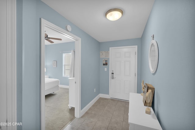 foyer featuring a ceiling fan, baseboards, and light tile patterned floors