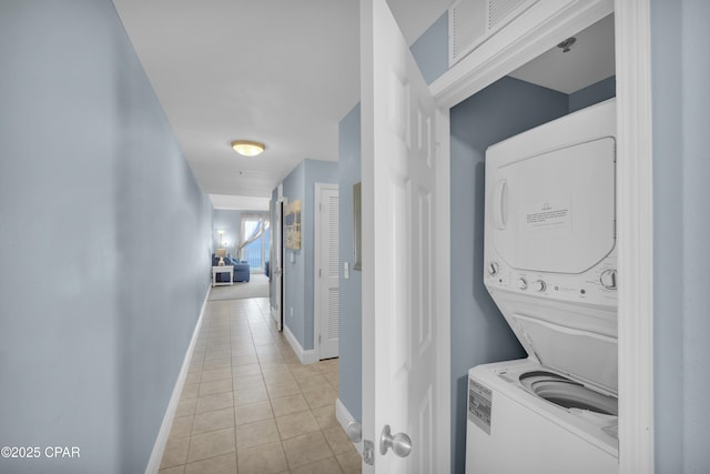 washroom featuring light tile patterned floors, laundry area, baseboards, stacked washer and dryer, and visible vents