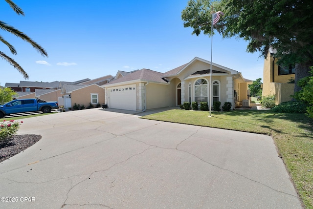 single story home with a garage, a front lawn, driveway, and stucco siding
