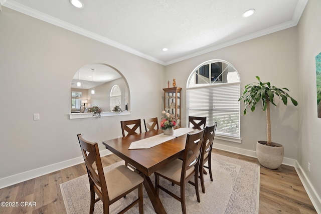 dining room featuring wood finished floors, crown molding, recessed lighting, and baseboards