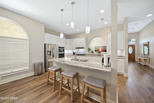 kitchen featuring a breakfast bar area, stainless steel appliances, a healthy amount of sunlight, and dark wood-style floors