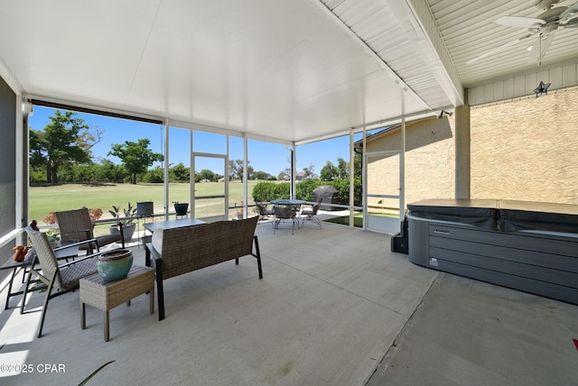 sunroom / solarium featuring view of golf course, outdoor dining space, ceiling fan, and a jacuzzi