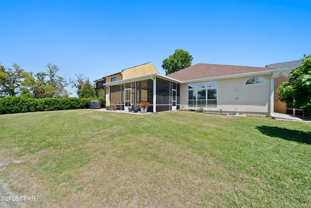 back of house featuring stucco siding, a sunroom, and a lawn