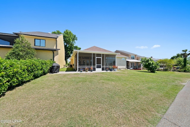 back of property featuring a sunroom, a yard, and stucco siding