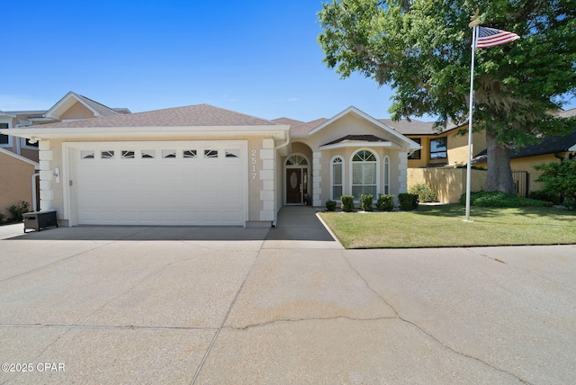 ranch-style house with stucco siding, fence, a garage, a front lawn, and concrete driveway