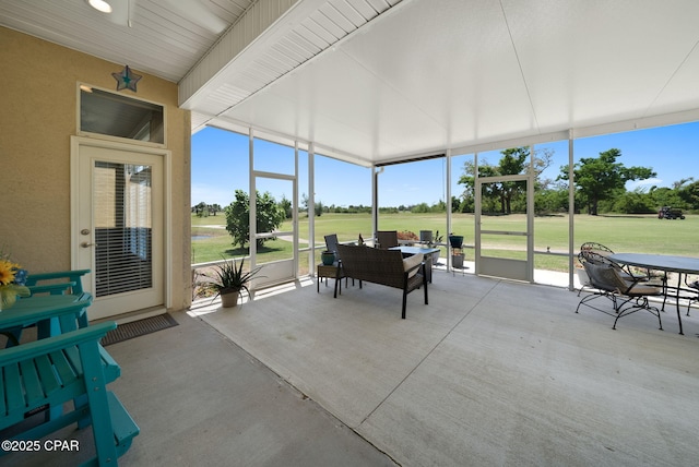 sunroom featuring outdoor dining area and golf course view