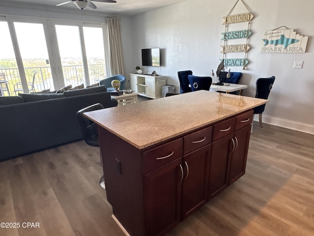 kitchen with open floor plan, a kitchen island, ceiling fan, and dark wood finished floors