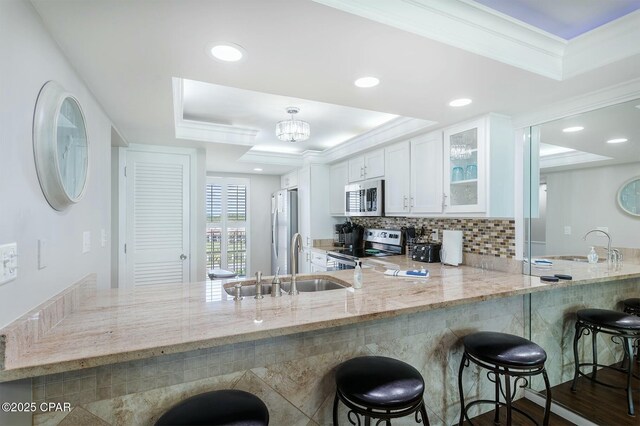 11619 Front Bch Unit 610, Panama City Beach, FL 32407 - kitchen with stainless steel appliances, a raised ceiling, a peninsula, glass insert cabinets, and light stone counters