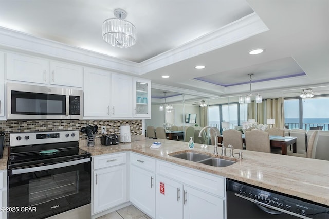 11619 Front Bch Unit 610, Panama City Beach, FL 32407 - kitchen with stainless steel appliances, a chandelier, a tray ceiling, ornamental molding, and light stone countertops