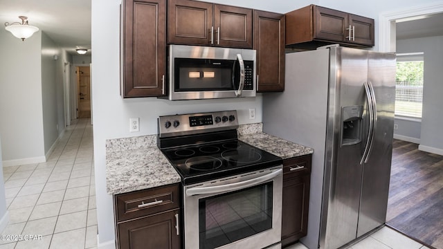 kitchen featuring appliances with stainless steel finishes, baseboards, dark brown cabinetry, and light tile patterned floors