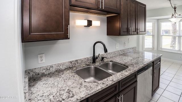 kitchen featuring stainless steel dishwasher, light stone counters, dark brown cabinets, a sink, and light tile patterned floors