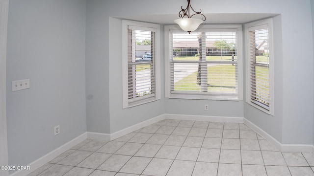 unfurnished dining area with baseboards and light tile patterned flooring