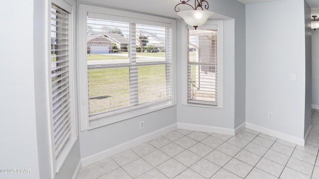 unfurnished dining area featuring light tile patterned floors, a wealth of natural light, and baseboards
